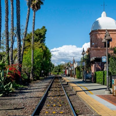 San Juan Capistrano, CA / USA - March 17, 2020: A single set of train tracks leads to a vanishing point on the horizon at a train station, whose architecture mimics a Catholic church.